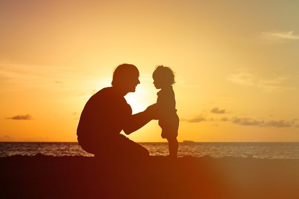 Father and child on the beach against a sunset Father and child on the beach against a sunset