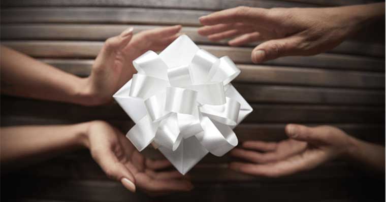 Hands holding a white gift together Hands holding a white gift together